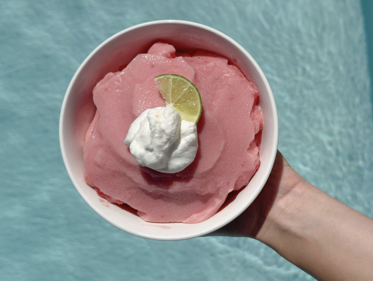 A bowl of fresh watermelon sorbet held out over the edge of a swimming pool.