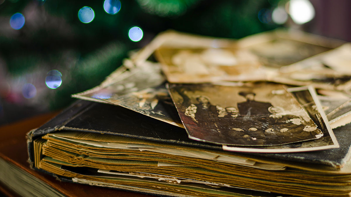 Old photo book laying on a table with a few old photos of family ancestors spread across the top