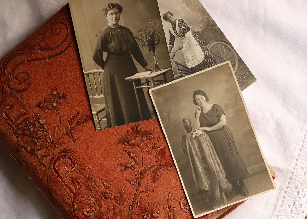 Old leather-bound photo book with three photos of a female ancestor laying on top