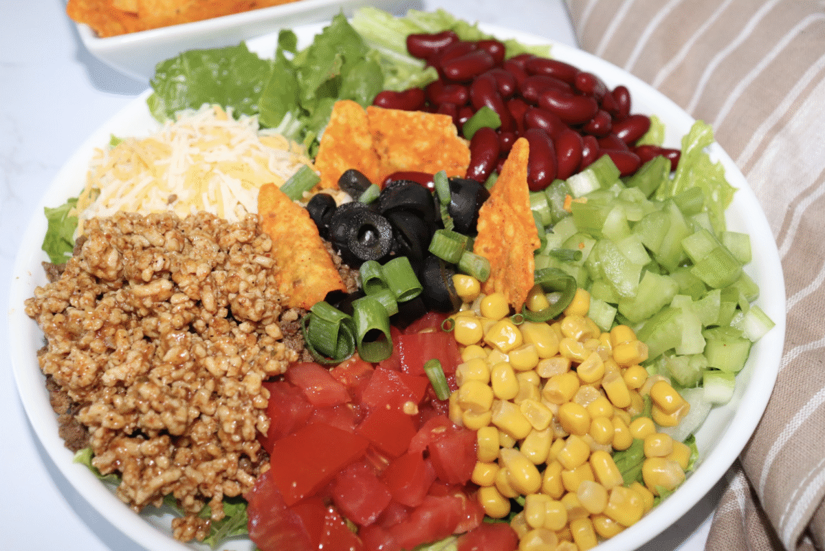 A large serving bowl with southwest summer salad on a marble countertop.