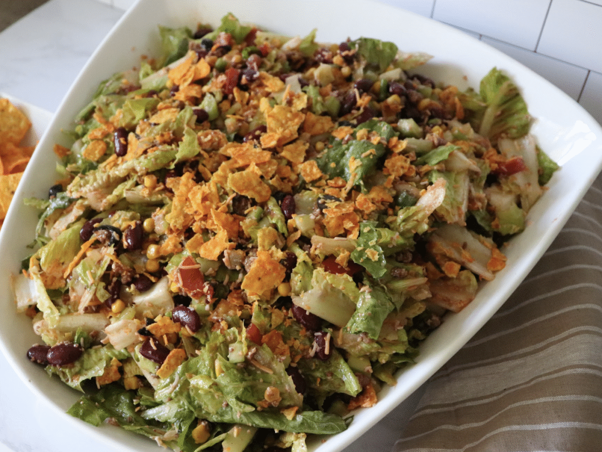 Chopped southwest summer salad topped with crushed corn chips with a striped linen.