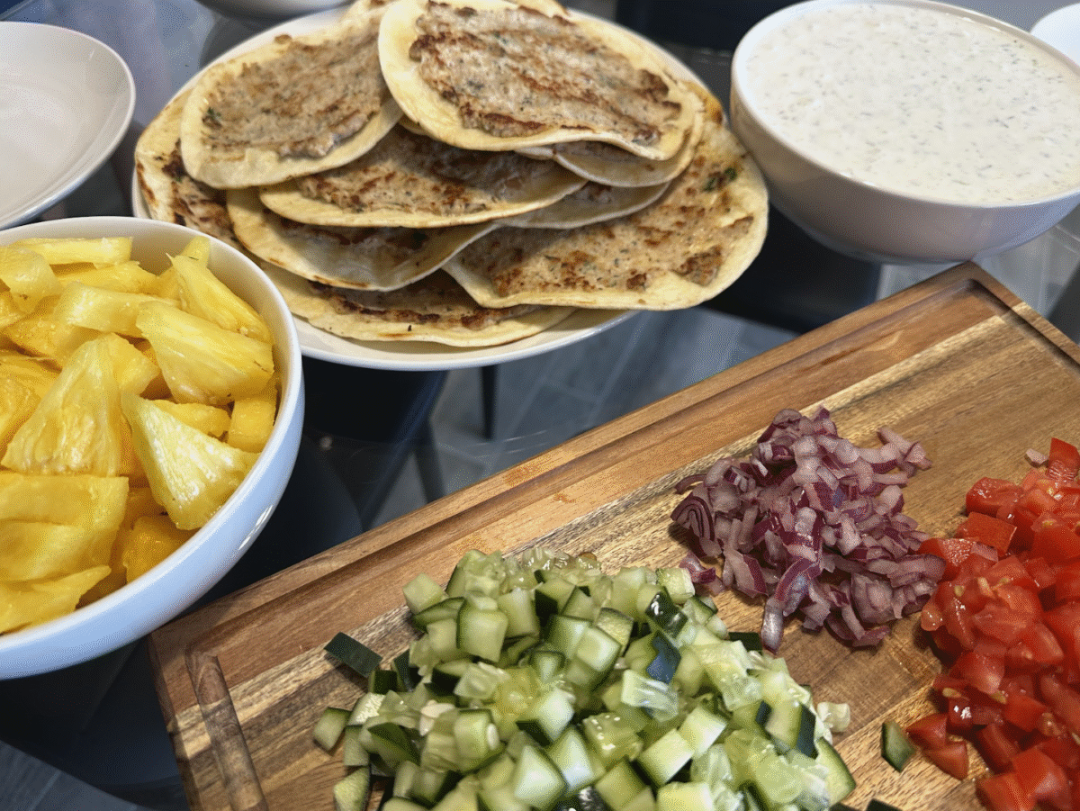 Chicken Gyro Tacos on a serving plate with diced pineapple, homemade french fries and tzatziki sauce. 