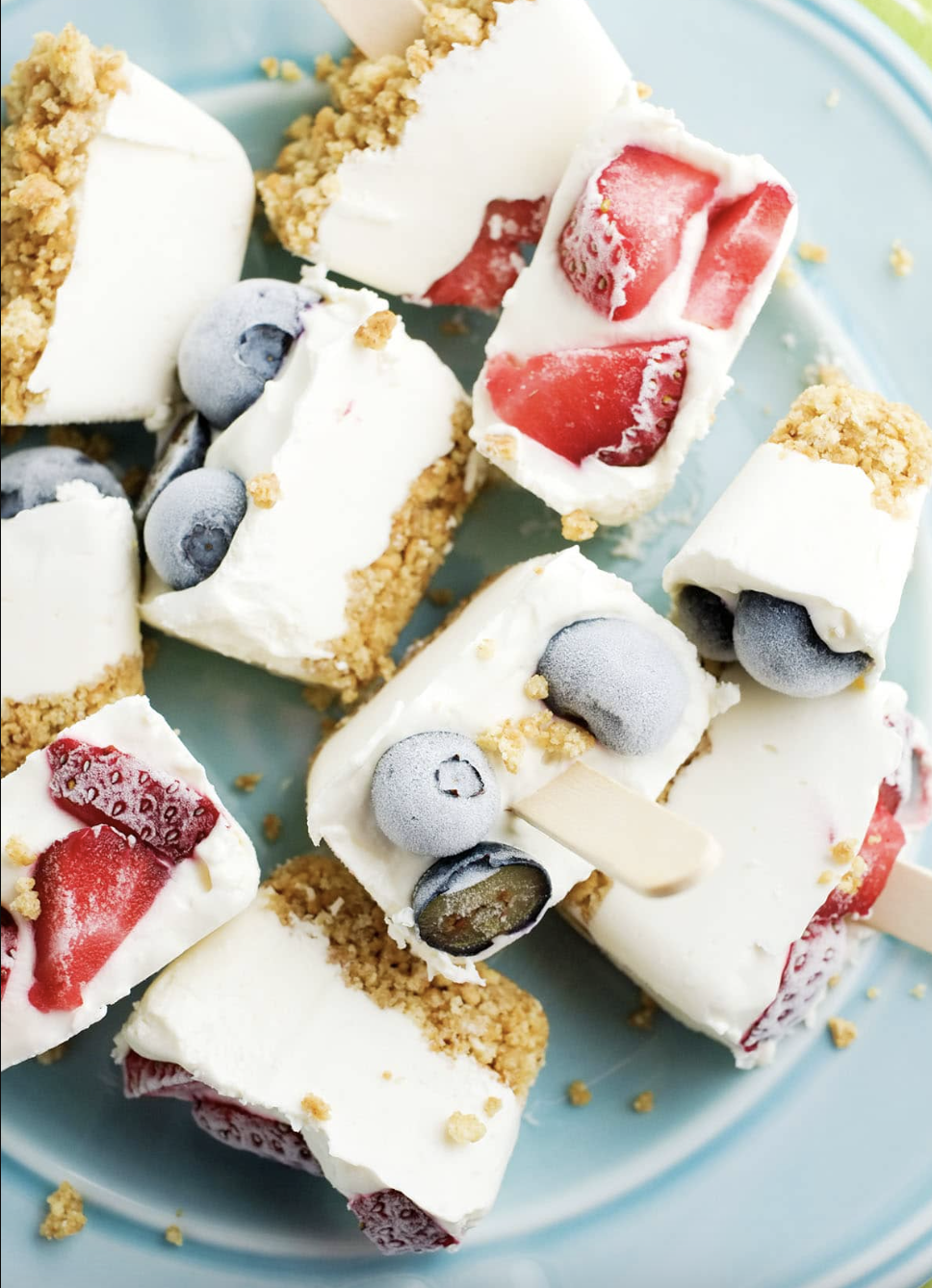 Frozen cheesecake bites with crushed graham crackers and fresh berries on a serving plate