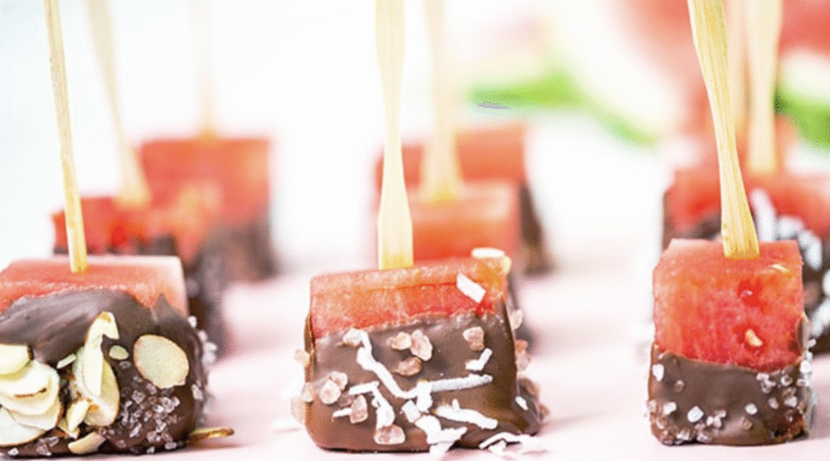 Frozen watermelon cubes with a large toothpick and dipped in chocolate and shredded coconut.