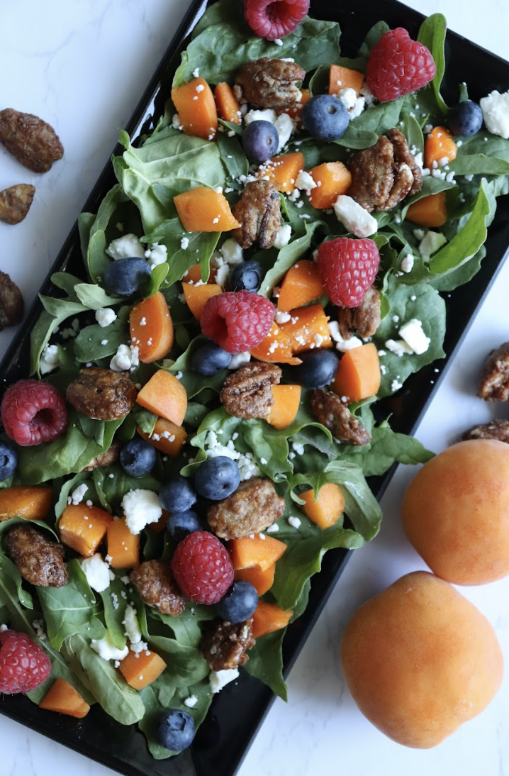 apricot and arugula salad with berries and feta on a serving platter