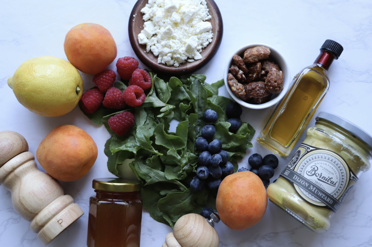 ingredients you need to make apricot berry arugula salad on a white countertop