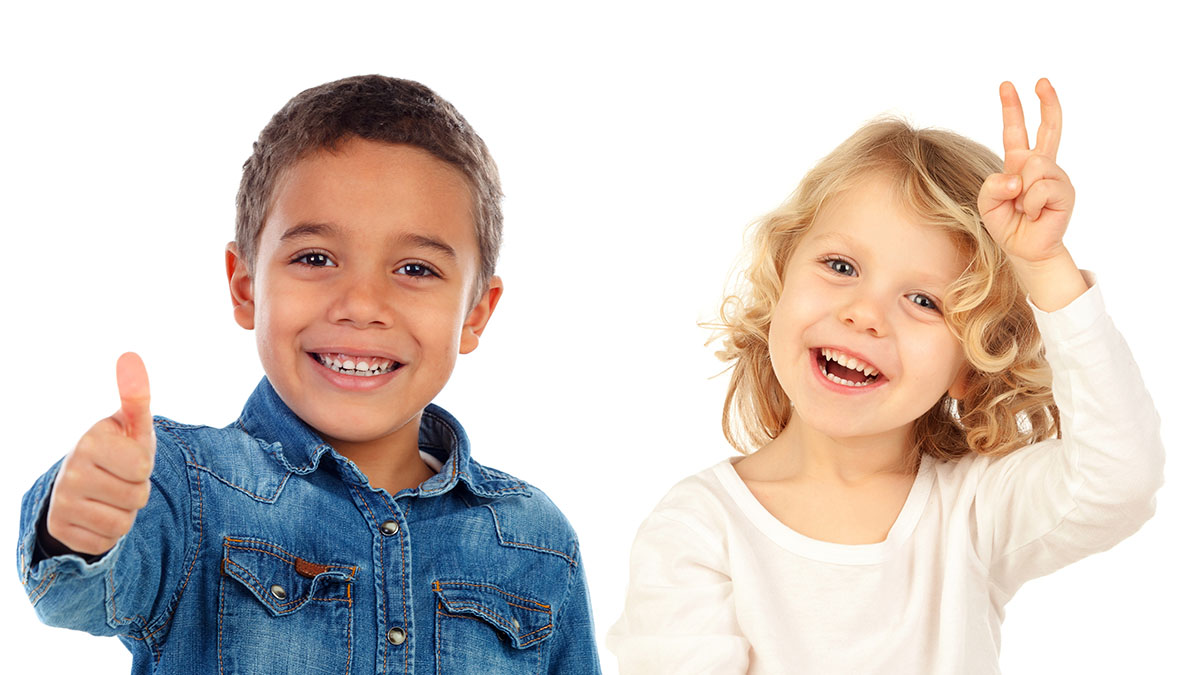 6 year old boy wearing a blue shirt giving a thumbs up and 6 year old girl in white shirt showing a happy peace sign both on a white background