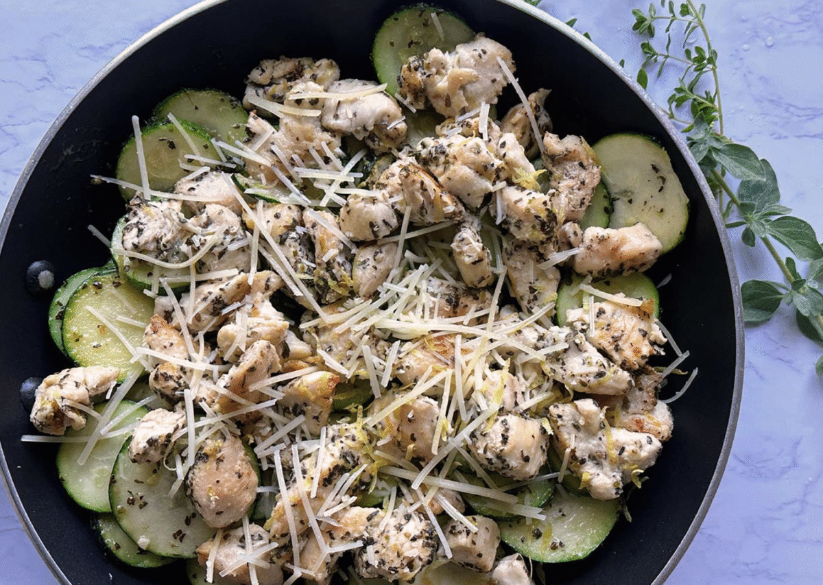 lemon chicken zucchini skillet dinner topped with parmesan cheese in a pan with fresh thyme garnish