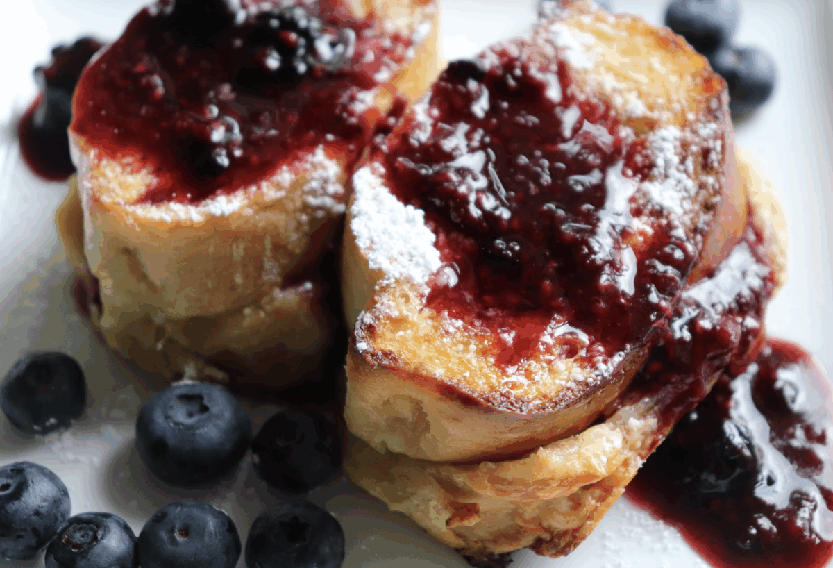 Overnight stuffed french toast topped with berry sauce and powdered sugar.