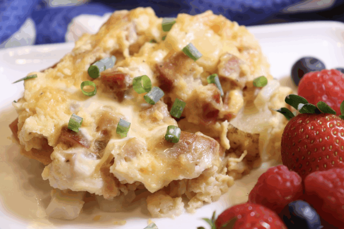 overnight breakfast casserole with ham and potatoes served with fresh strawberries