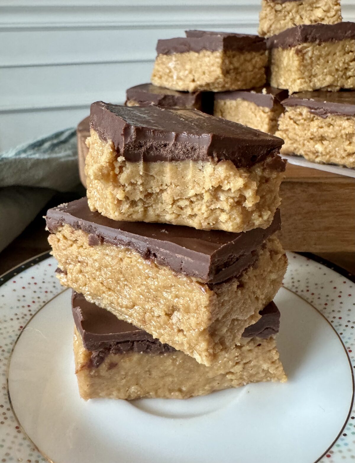 no bake peanut butter chocolate bars stacked on a plate with a bite taken out