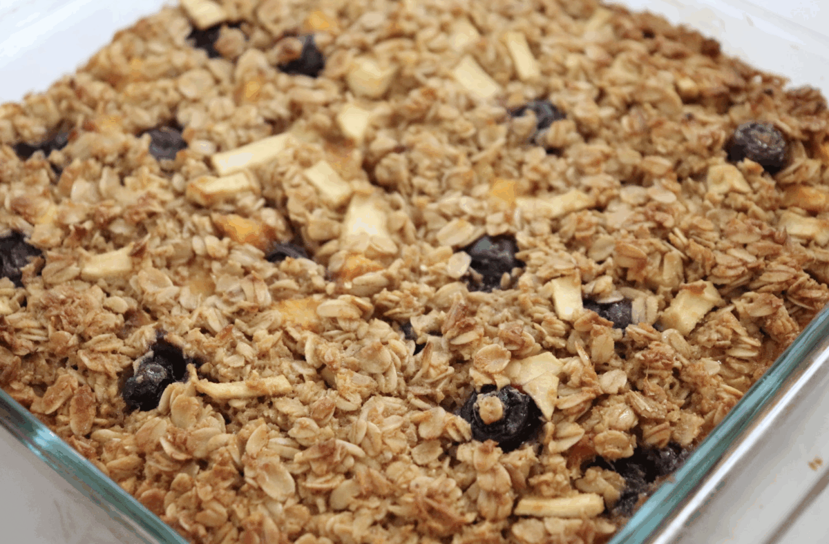 Fruity baked oatmeal in a glass baking dish with fresh blueberries, apples and peaches. 