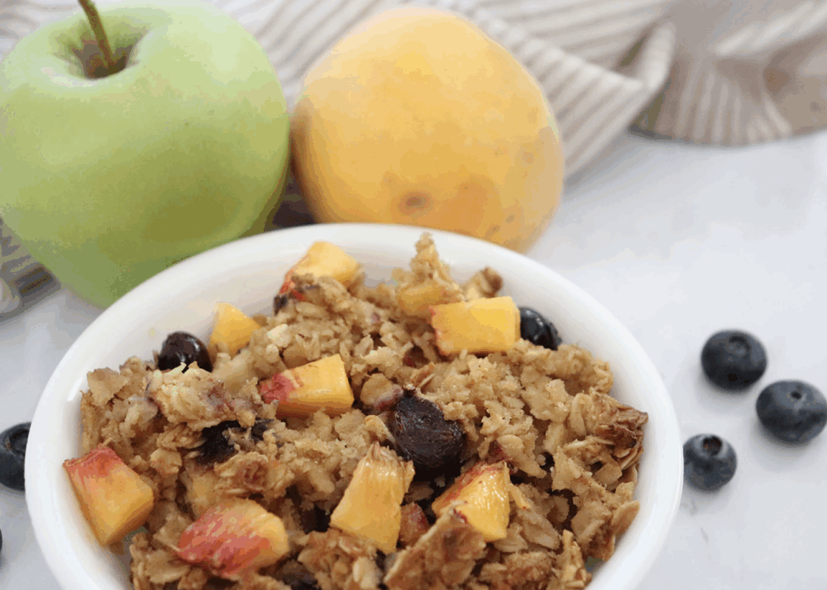 fruity baked oatmeal in a small serving bowl with diced peaches and fresh blueberries