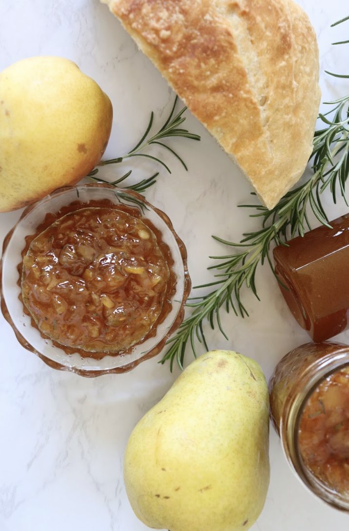 homemade pear preserves with rosemary and honey in a glass dish with fresh pears and a crusty bread
