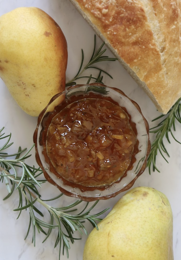 homemade pear preserves with rosemary and honey in a glass dish with fresh pears and a crusty bread
