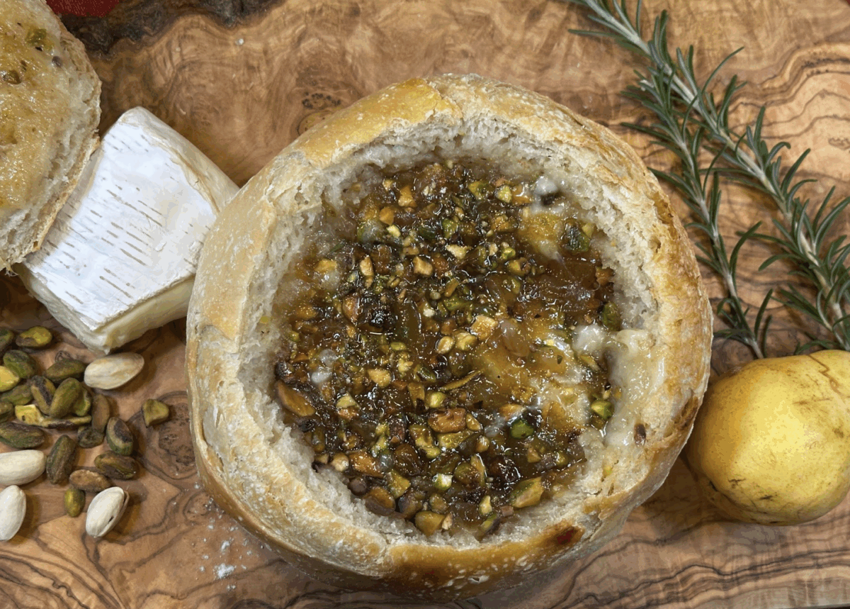 pistachio pear and brie stuffed sourdough bread on a wooden serving board