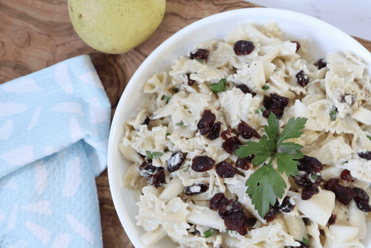 pear gorgonzola and chicken farfalle with fresh parsley in a serving bowl with a blue linen