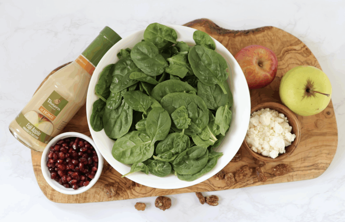 ingredients needed to make holiday spinach salad on a wooden board
