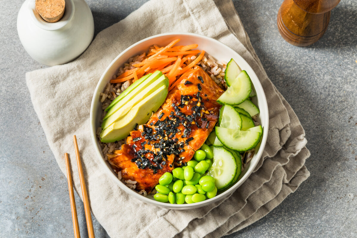 salmon with teriyaki sauce and fresh veggies in a bowl with a linen and chopsticks