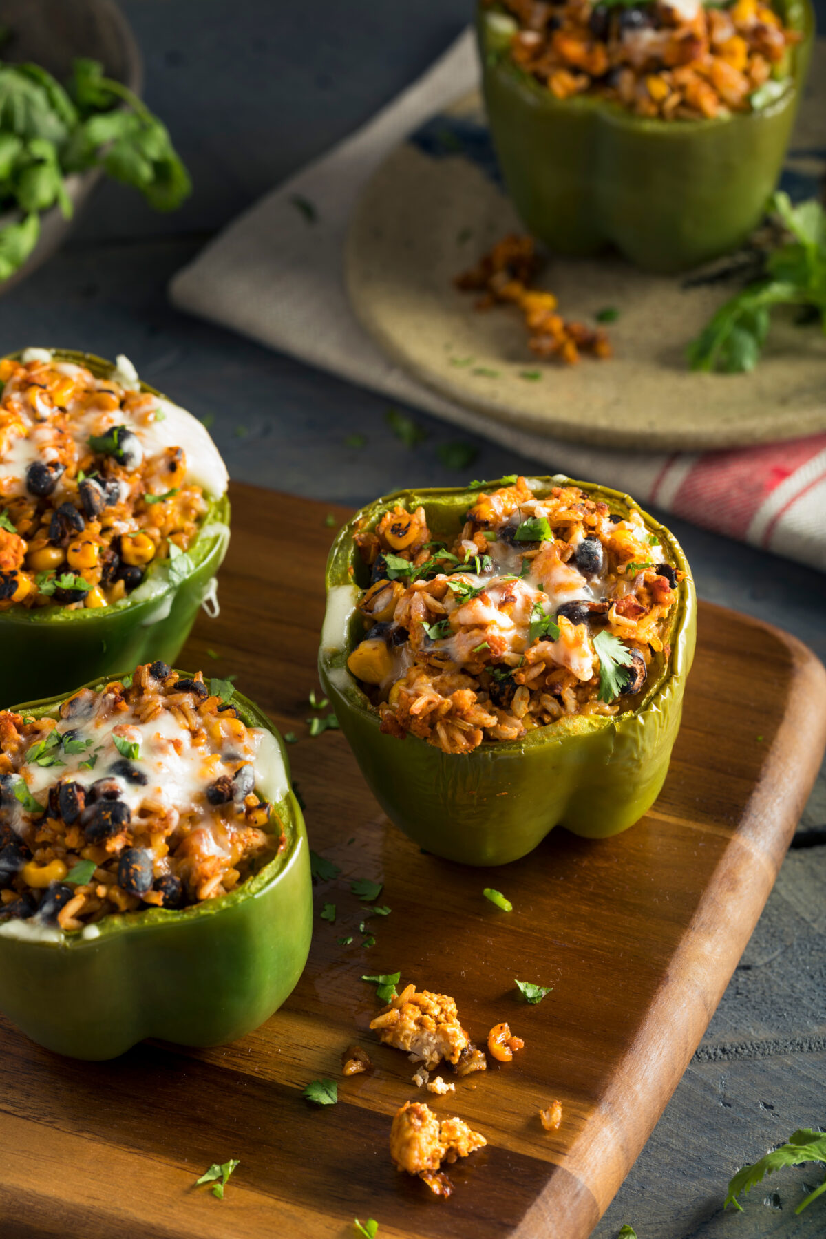 stuffed peppers with black beans and melted cheese on a wooden serving board