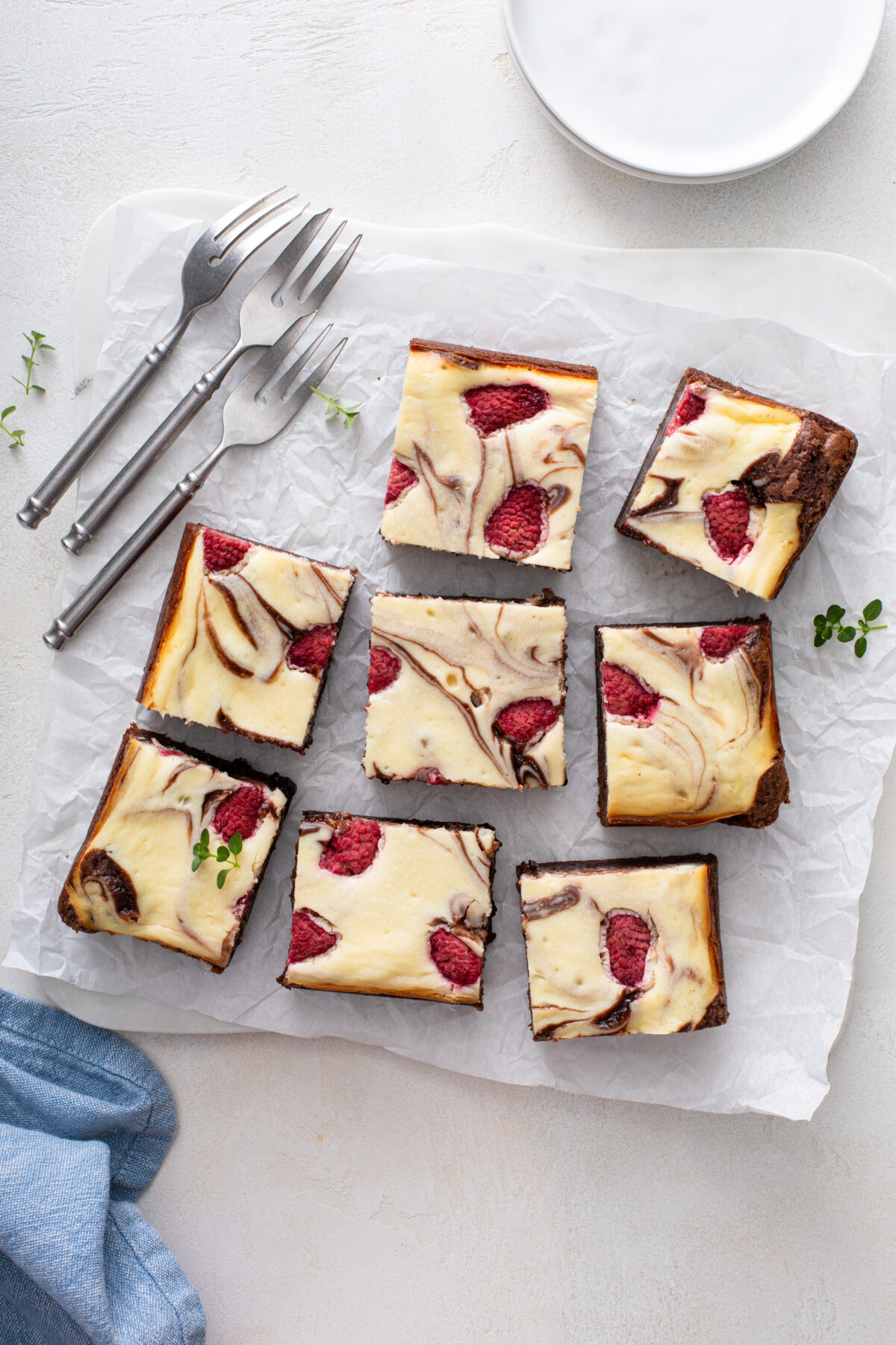 raspberry cheesecake brownies cut into squares on a sheet of parchment paper
