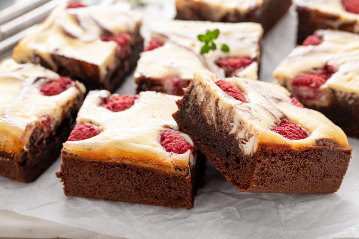 a plate of cheesecake brownies with fresh raspberries 