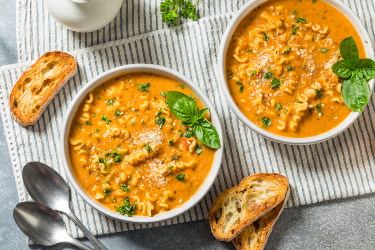 two bowls of creamy italian sausage soup with fresh basil and served with toasted bread