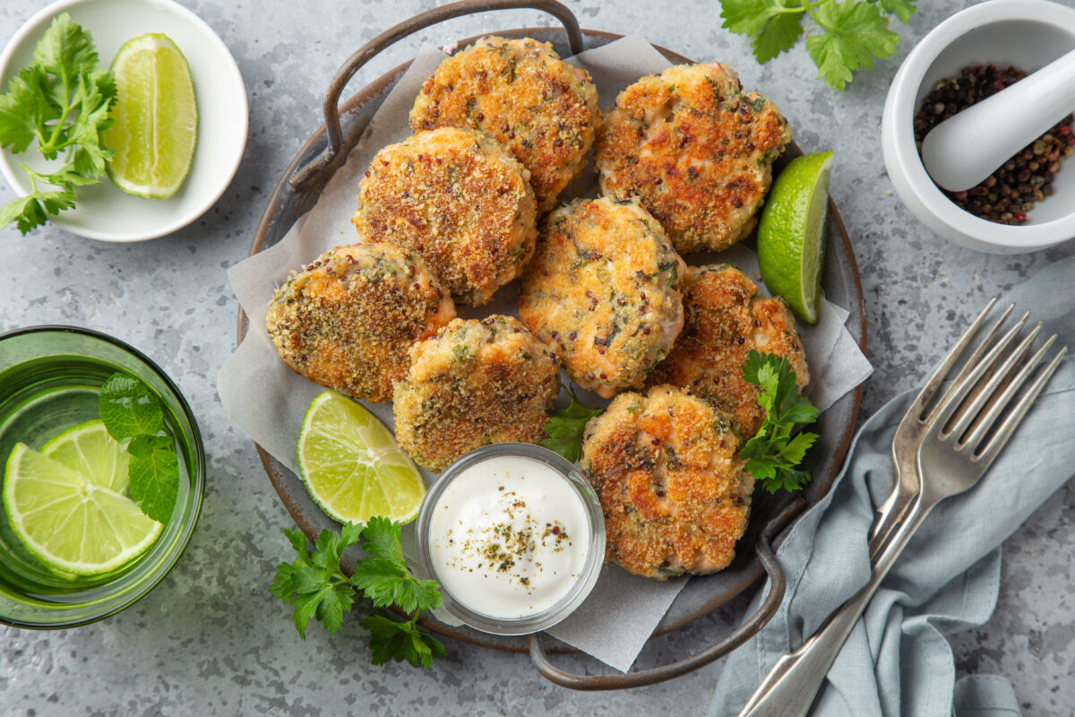 a plate of salmon patties served wtih a creamy dip and fresh lime