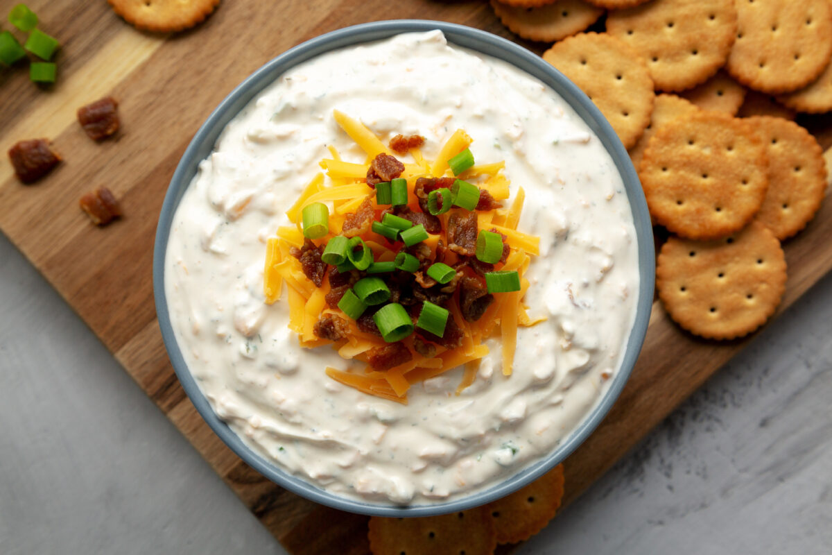 high protein crack dip with cheddar and bacon in a serving bowl with butter crackers