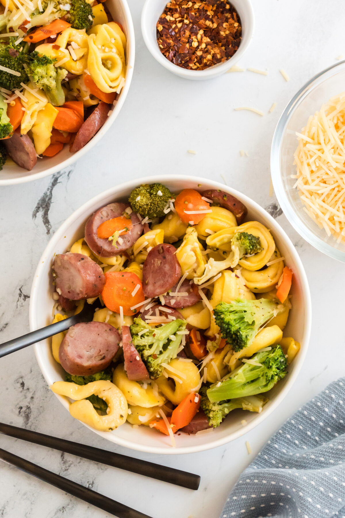 tortellini bake with broccoli, carrots and parmesan cheese in a bowl