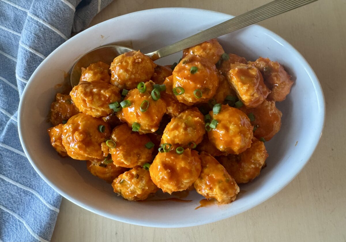 buffalo chicken meatballs in a white serving dish with a striped linen