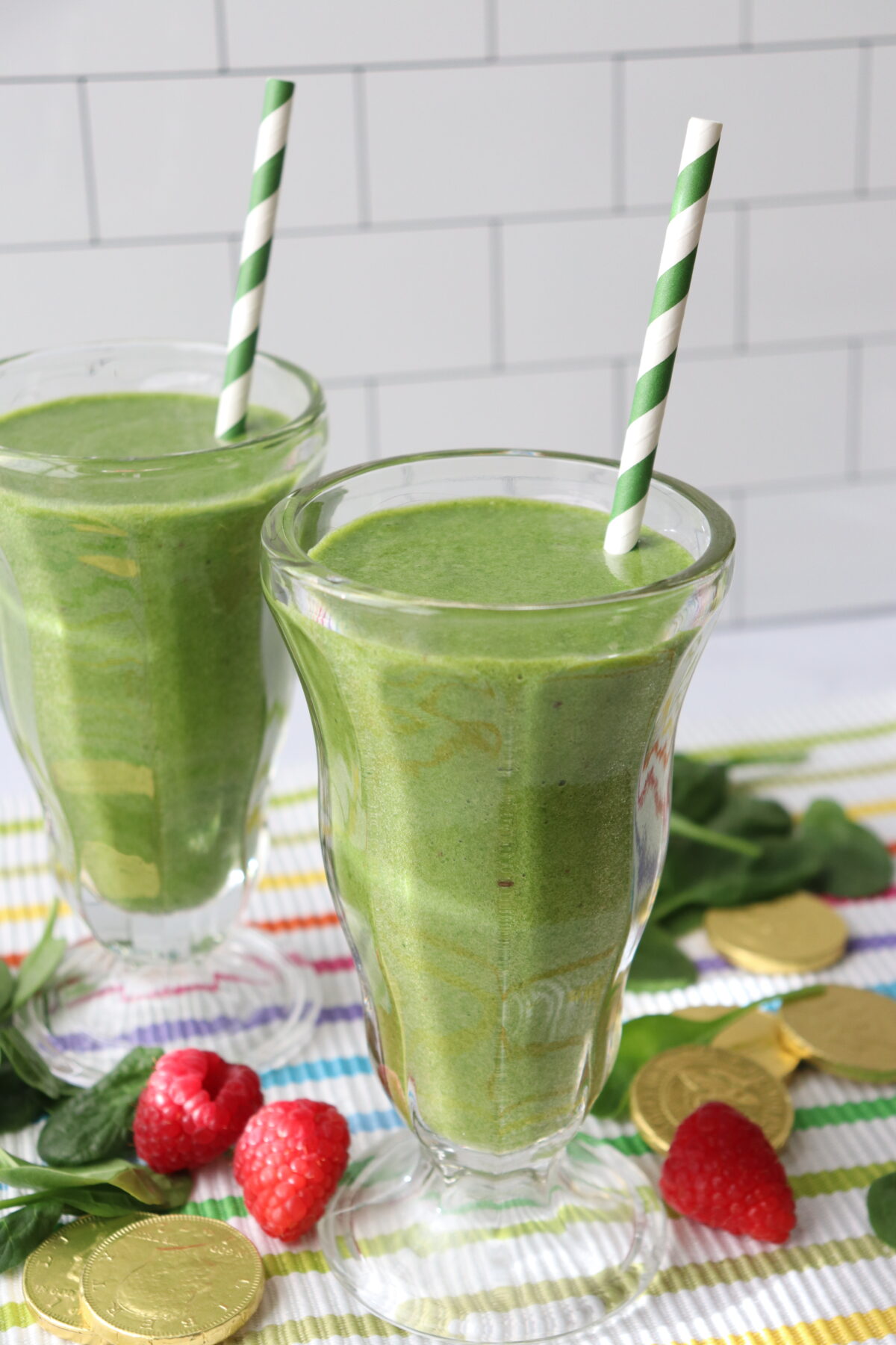 green power smoothie made with spinach with a green and white striped straw