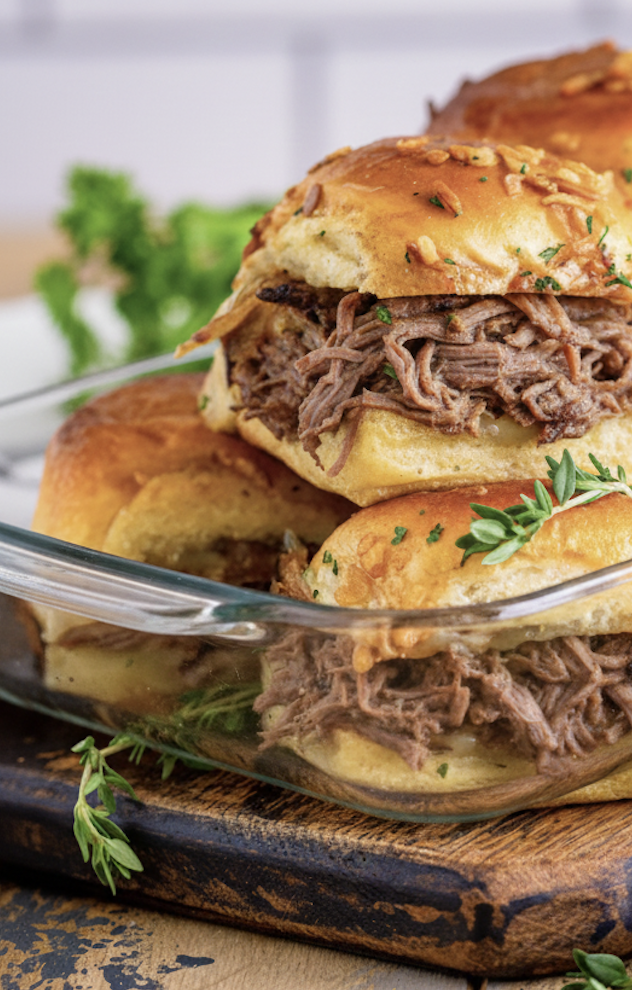 french dip sliders with fresh thyme in a baking dish