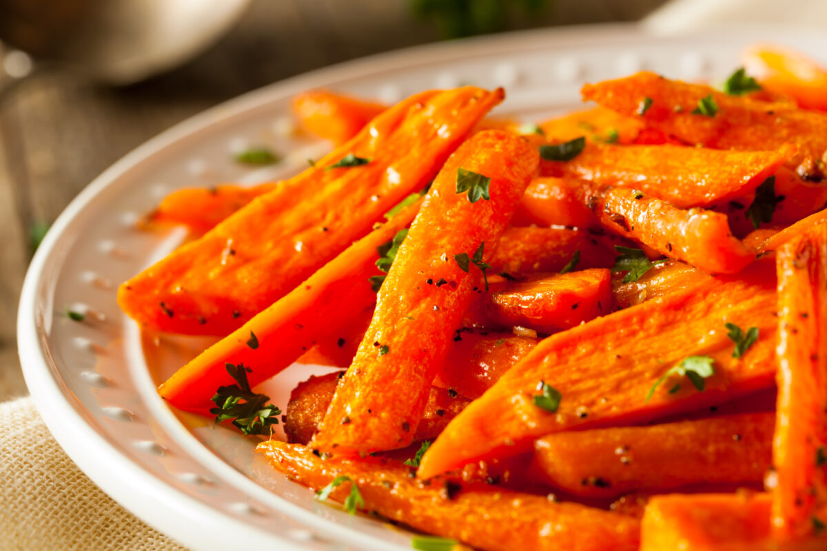 close up image of roasted carrots with maple syrup and fresh herbs