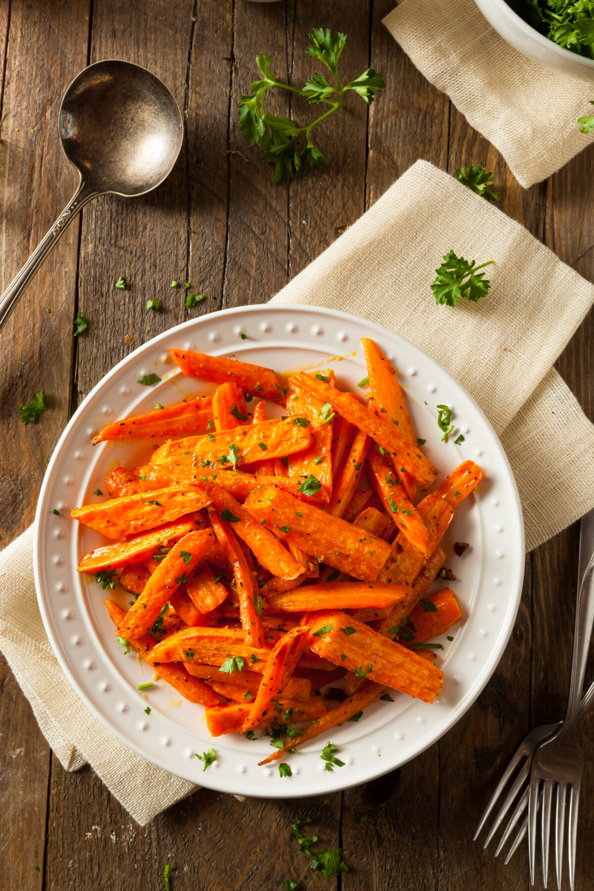 honey roasted carrots on a white plate with a linen and serving spoon