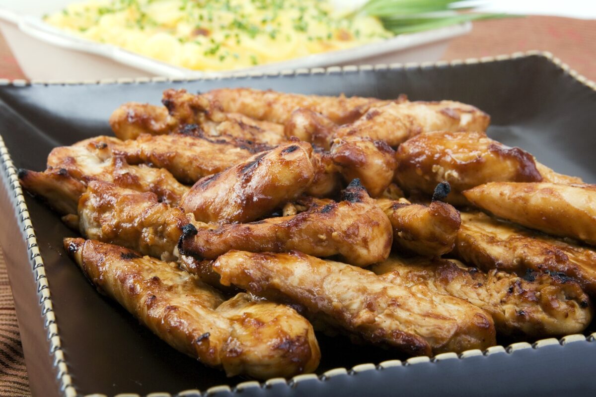 grilled chicken tenderloins on a black serving plate