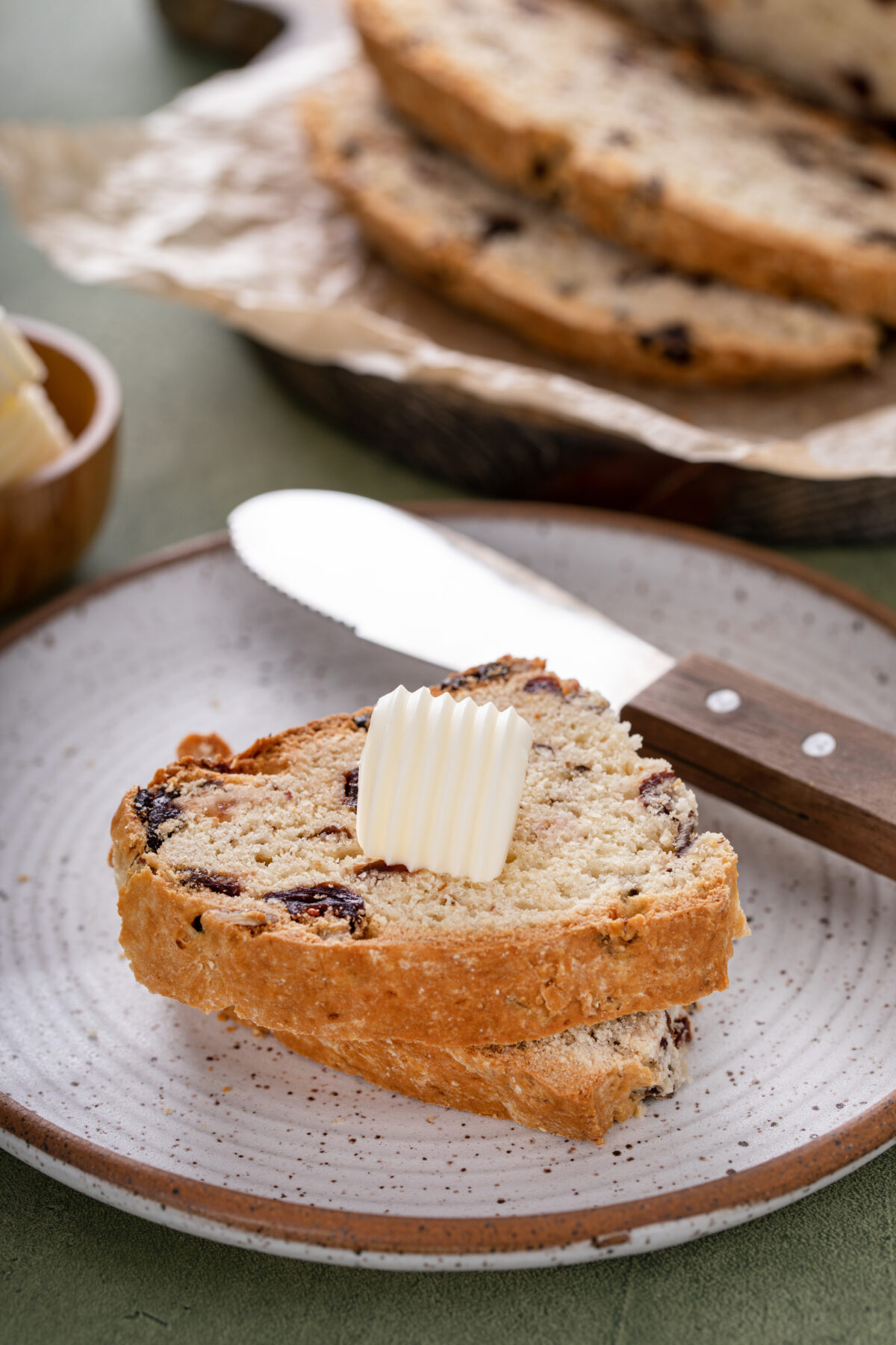 irish soda bread with cranberries cut into slices with butter on a serving plate