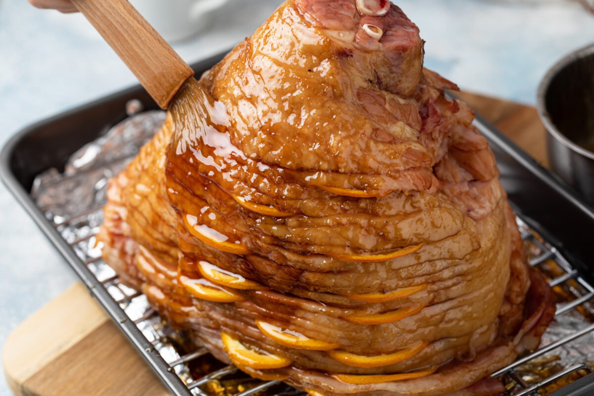 Making Easter or Christmas ham, glazing with orange glaze, stuffed with orange slices
