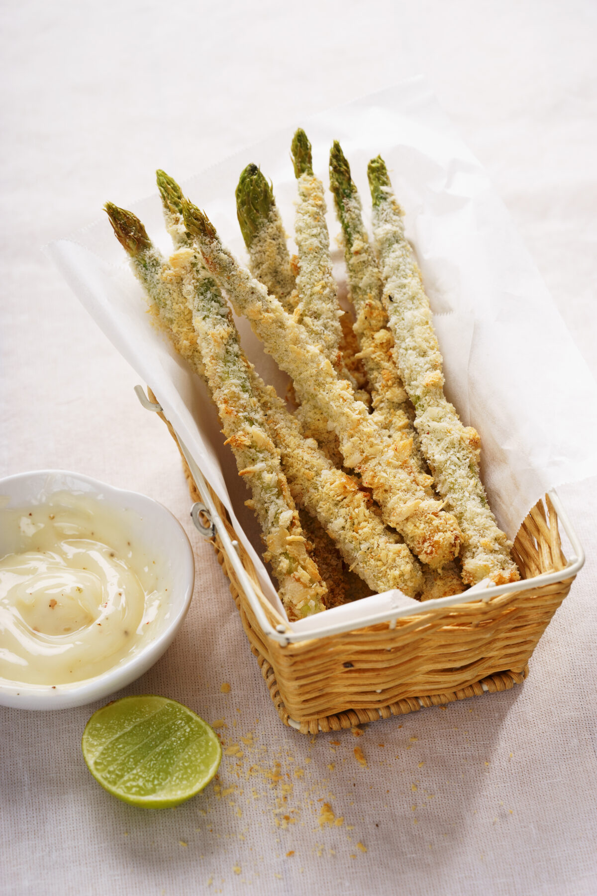 crispy parmesan asparagus in a small serving basket with a side of mayonnaise dip