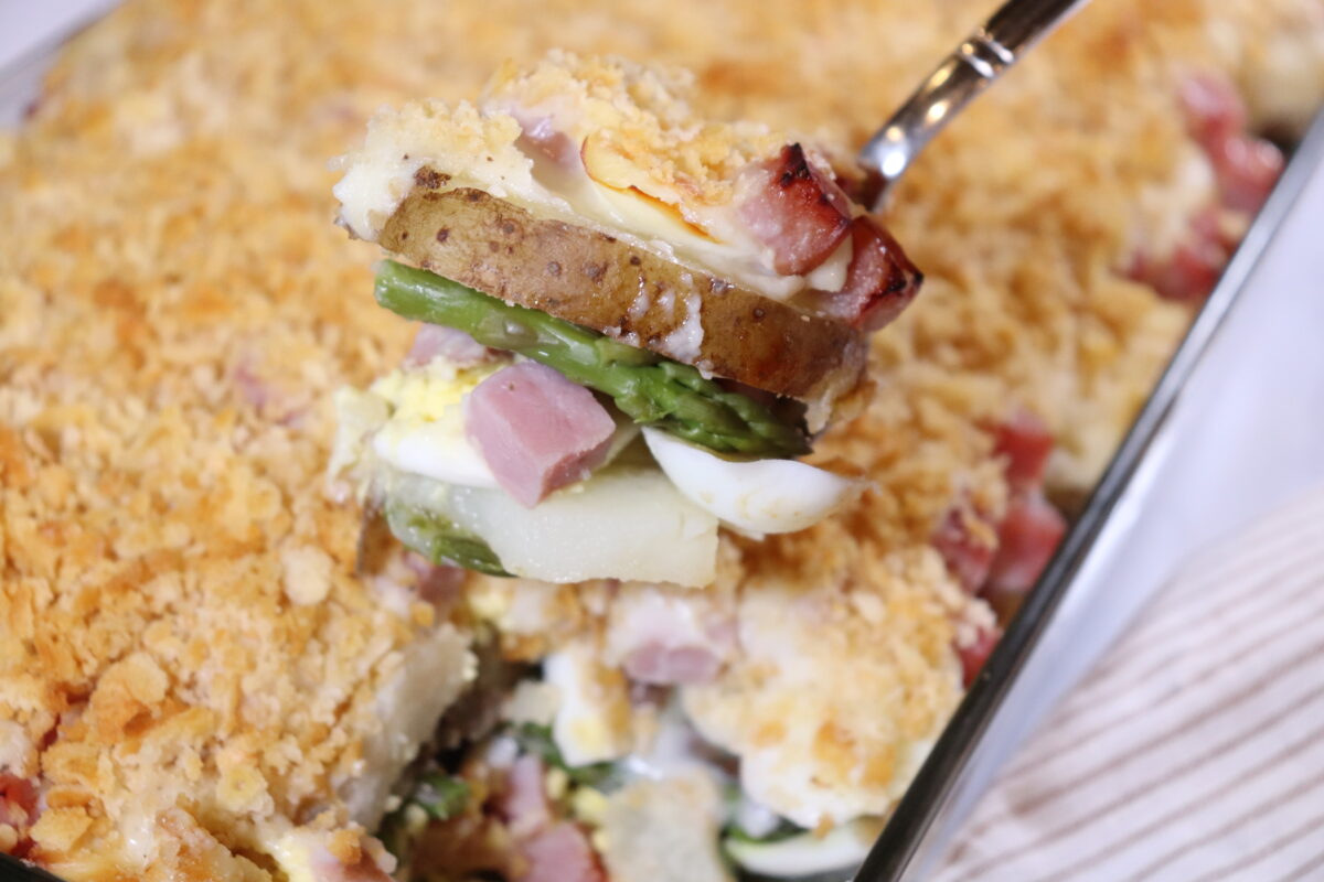 A spoonful of ham and asparagus casserole with potatoes and hard-boiled eggs.