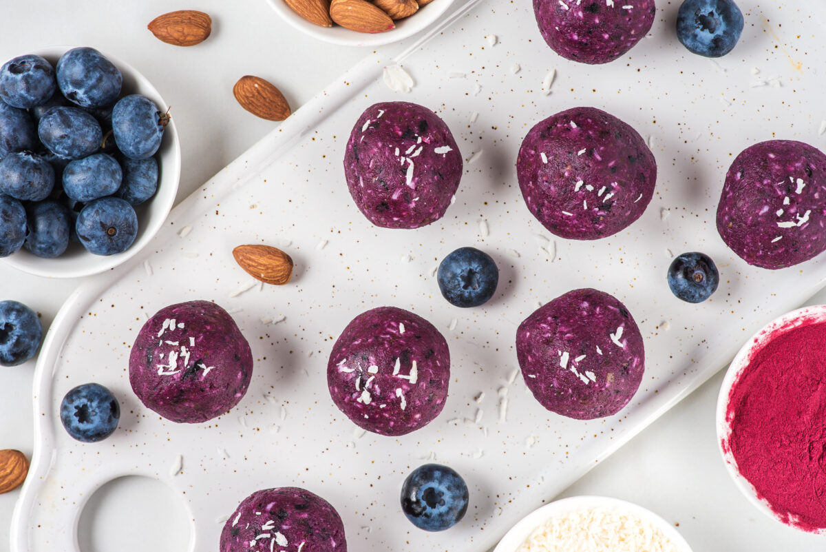No bake blueberry and acai energy bites or balls made of nuts, coconut flakes and dates. top view. healthy vegan food dessert