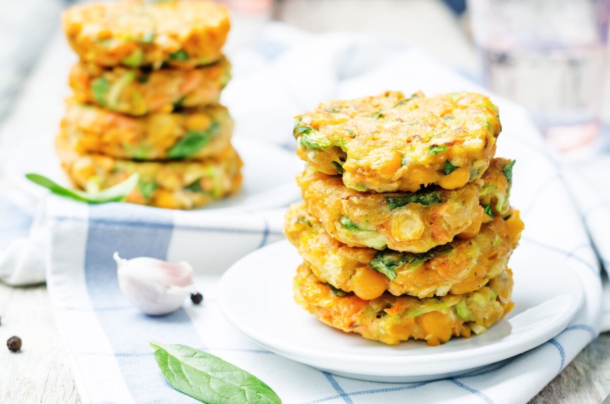 chickpea veggie patties stacked on a white plate with a checkered linen