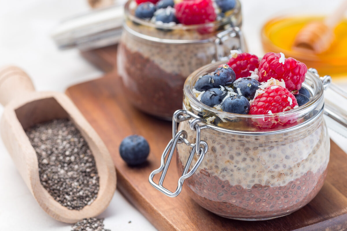 Chocolate Peanut Butter Chia Pudding topped with fresh berries, honey, and shredded coconut in a glass jar