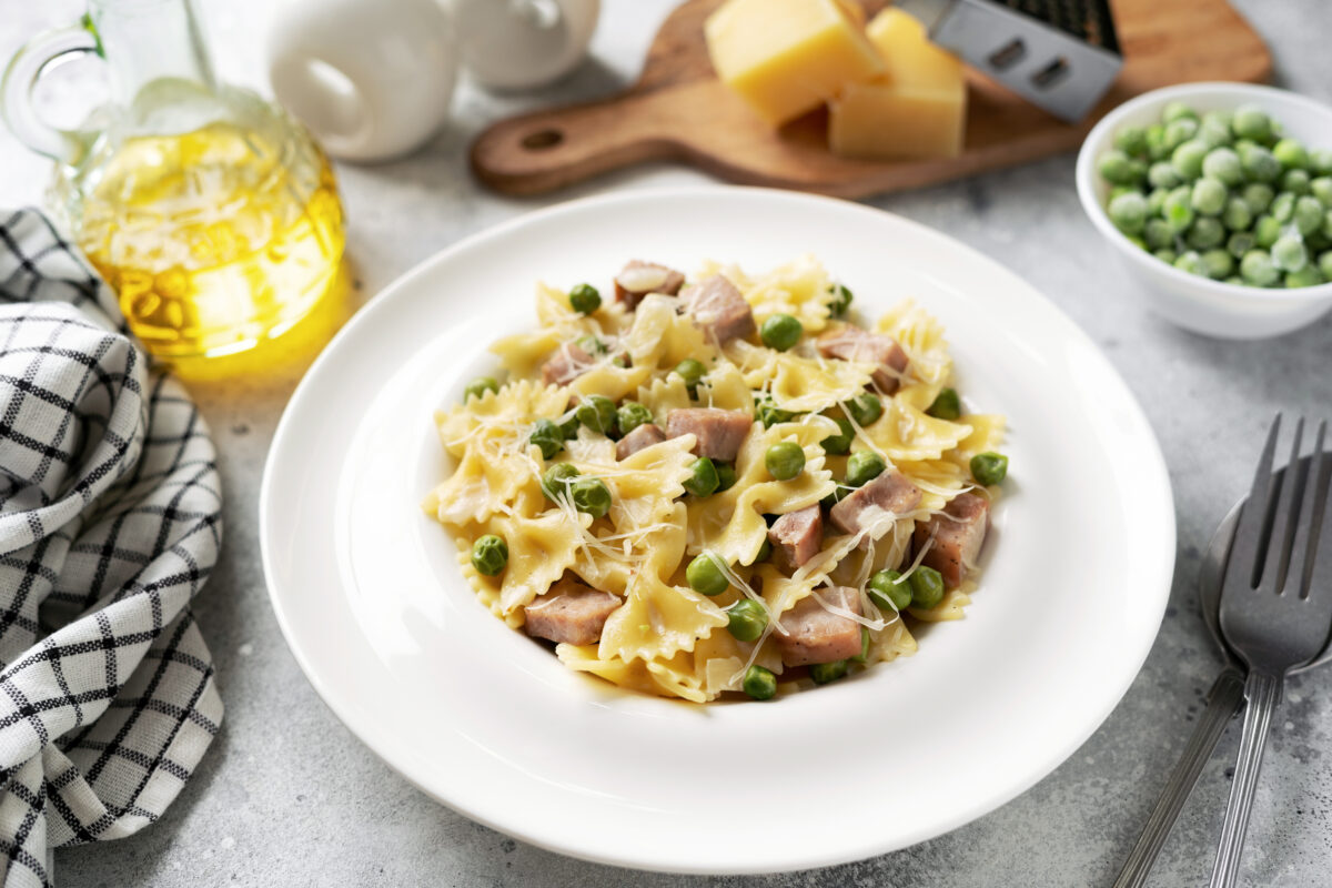 ham and pasta skillet dinner with fresh peas in a white serving bowl