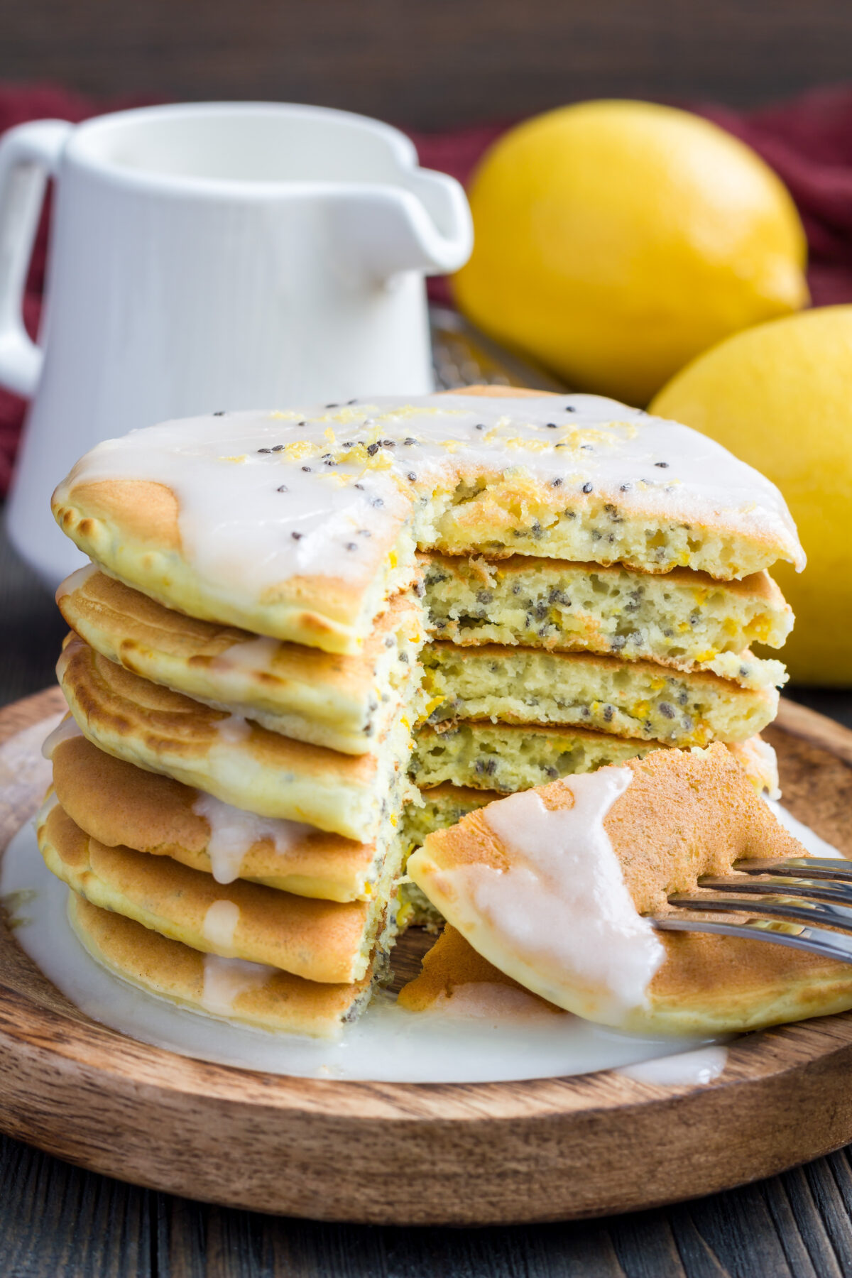 A stack of homemade lemon and chia seed pancakes with citrus glaze with a slice cut out