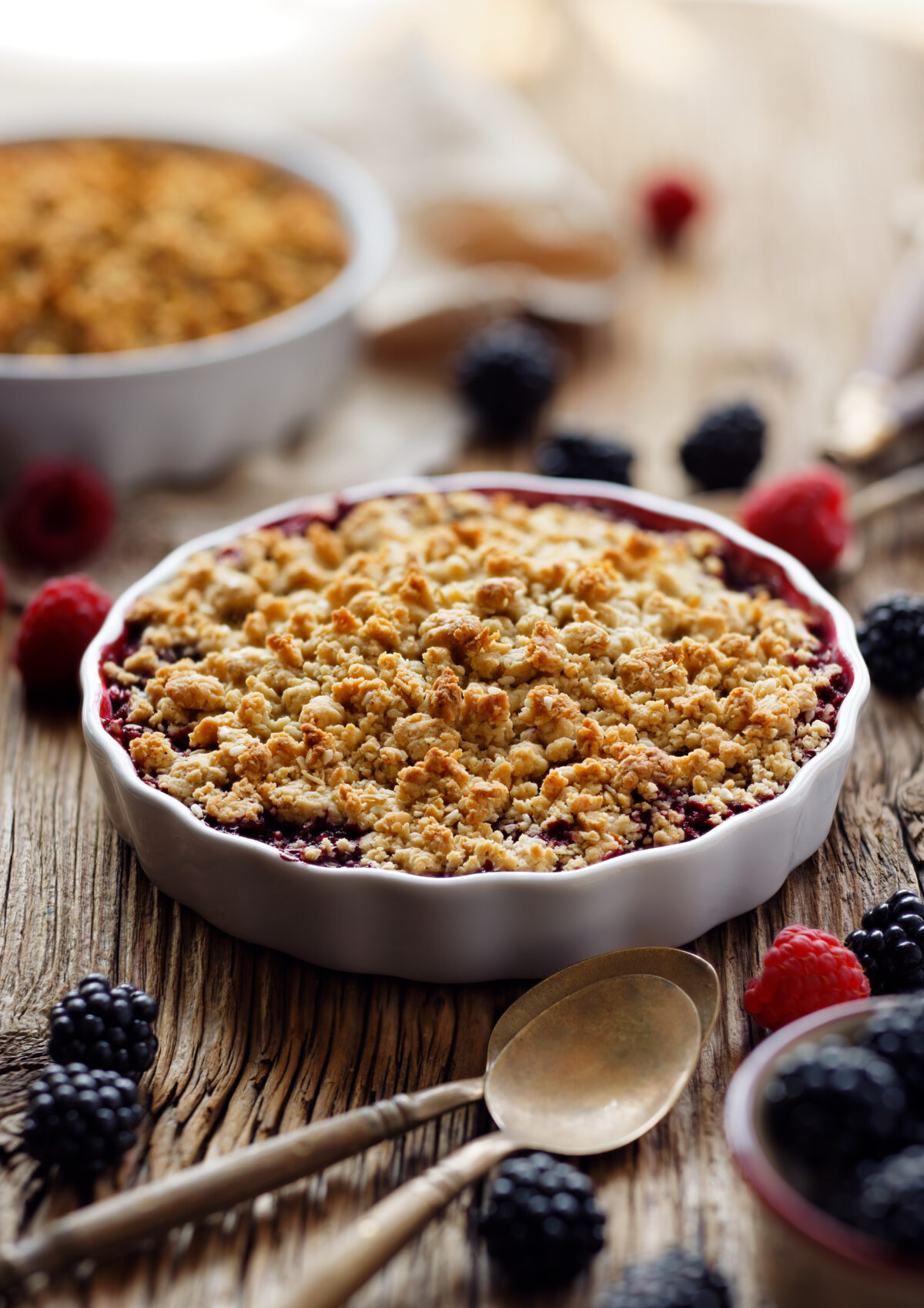 mixed berry crisp with an oat crumble topping in a round ceramic baking dish