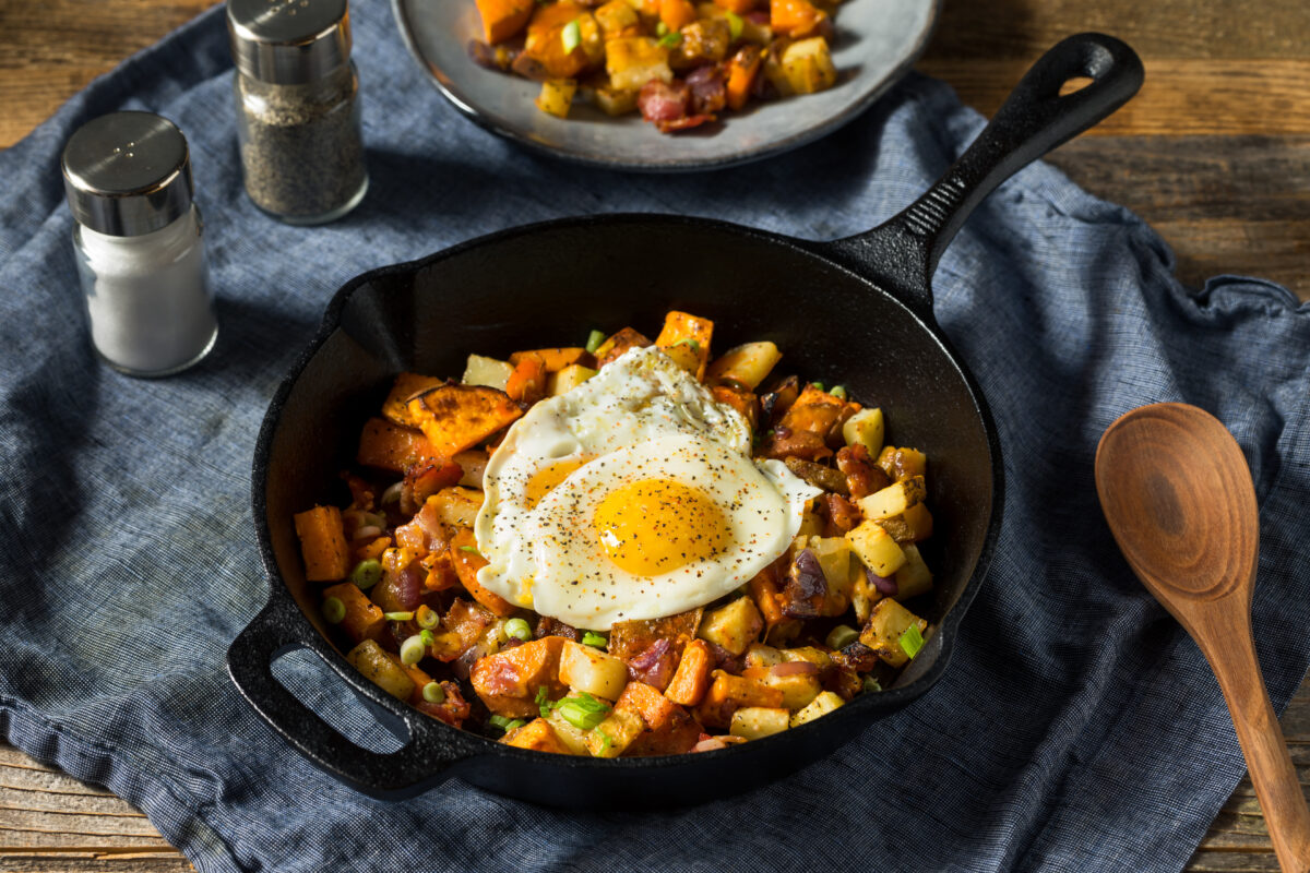 Homemade Healthy Sweet Potato Hash with Fried Eggs in a cast iron skillet with a blue linen