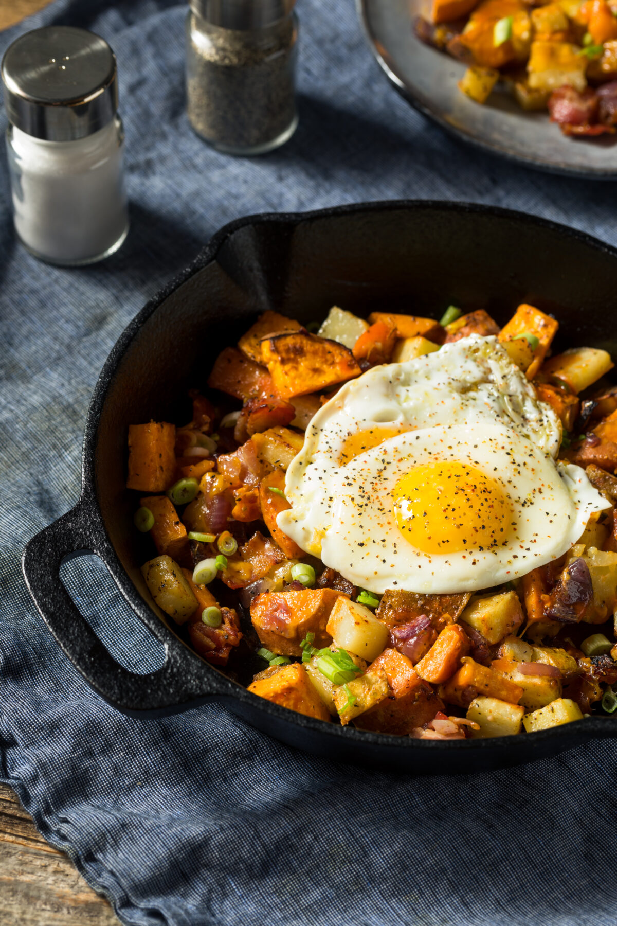 sweet potato breakfast hash in a cast iron skillet with a fried egg