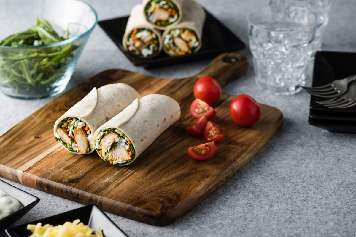 Fresh healthy chargrilled tandoori chicken wrap with tzatziki, cheese, baby spinach and carrots
