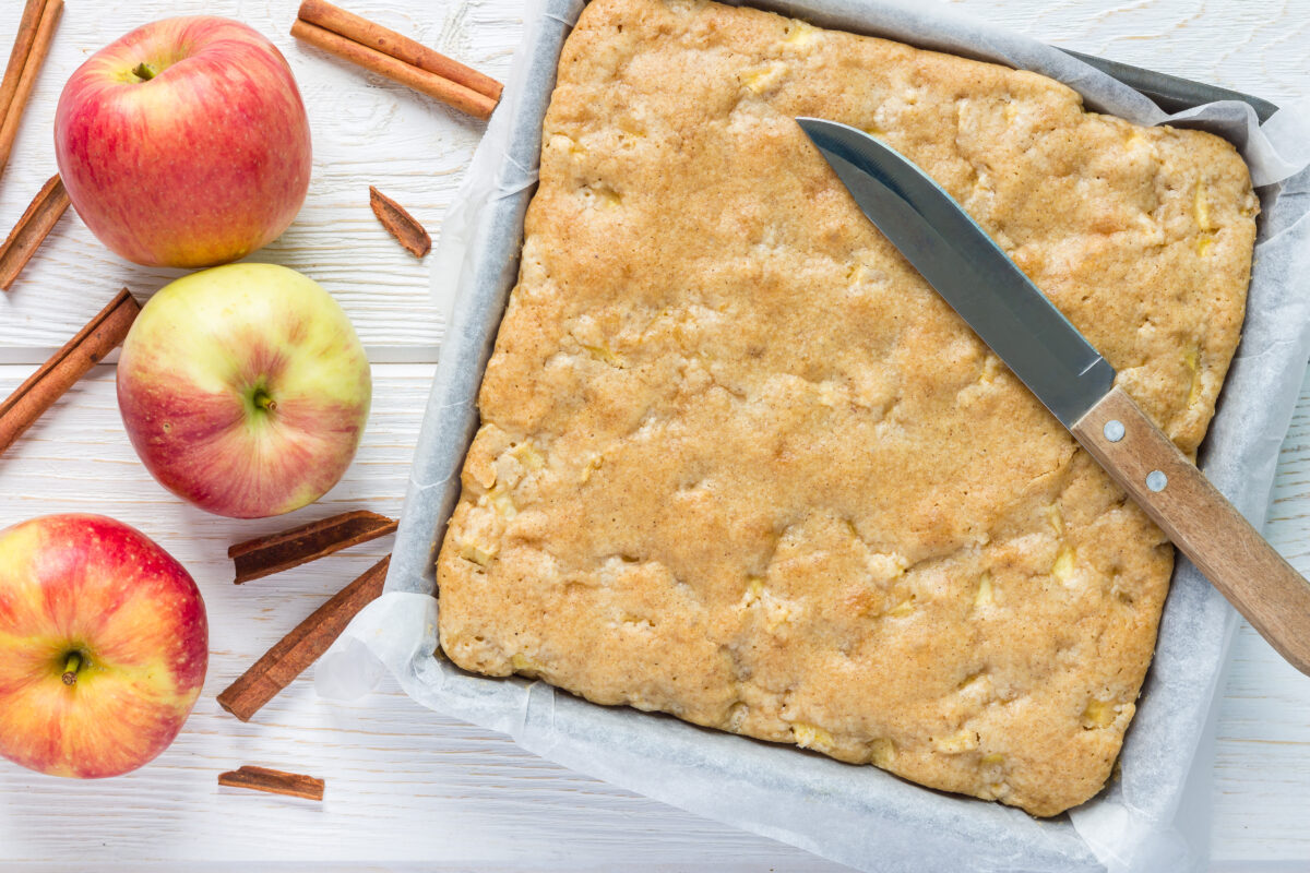 Apple blondies in a baking dish with parchment paper and fresh apples
